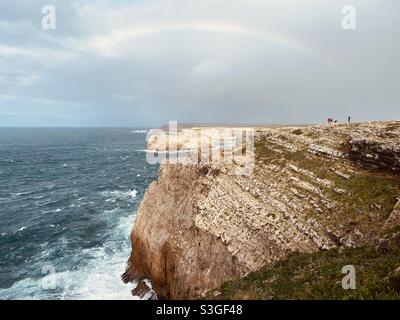 Western Algarve coastline with faint rainbow in the stormy sky Stock Photo
