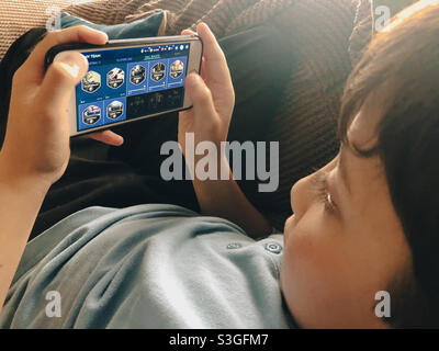 A boy relaxing and playing a game on a mobile phone. Stock Photo