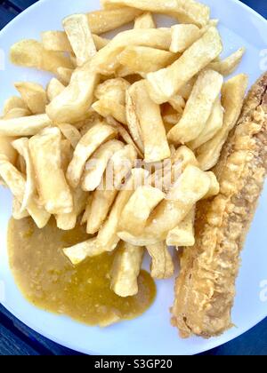 Chip shop style chips with battered sausage and curry sauce Stock Photo