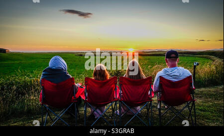 Family of four watching the sunset over Islay from Machrihanish in Kintyre in Scotland Stock Photo