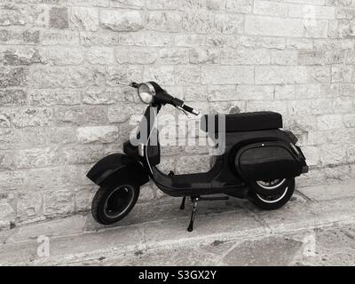 A vespa Motor Scooter in Front of a brick wall in the City of Monopoli, Puglia, Italy Stock Photo