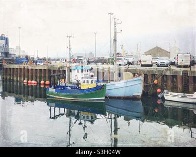 Small fishing boats in Stromness Harbour on an overcast day, image processed to have a grungy, nostalgic feeling Stock Photo