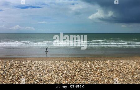 Walkers on the shingle beach at Bracklesham Bay, West Sussex Stock Photo