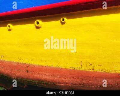 Sunlit detail of a brightly painted boat moored in a Cornish harbour, August. Stock Photo