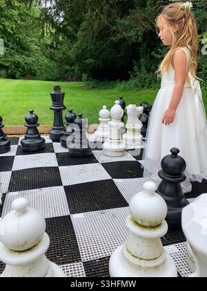 Young child pretending to be the white queen, on an outside giant chess game. Stock Photo