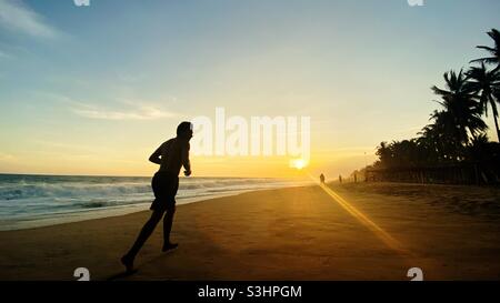 Backlit of man running on the beach at sunset in Mexico. Pie de la Cuesta, Acapulco Guerrero. Stock Photo