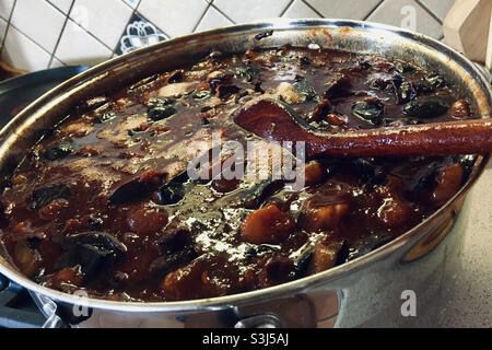 Making plum jam without sugar or preservative. Wooden spoon in boiling plum jam in kitchen. Stock Photo