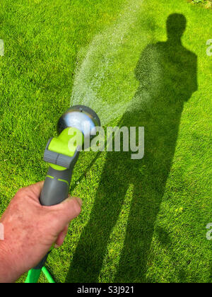 Looking down whilst watering a vibrant green lawn. Summer sunshine helps make this place an inspiration. Photo ©️ COLIN HOSKINS. Stock Photo