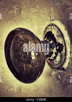 Worn and damaged old looking victorian shiny brass door handle fixed to an ancient wooden door Stock Photo