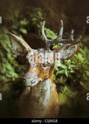 Decrepit and spooky deer statue in woods Stock Photo