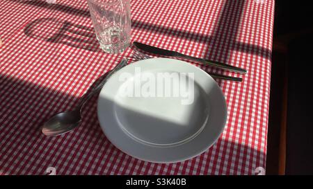 Empty plate and a Glass, fork and knife on a Table with checkered Table cloth Stock Photo