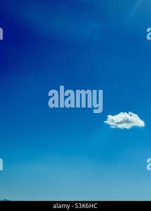 Single puffy cloud in a bright blue sky Stock Photo