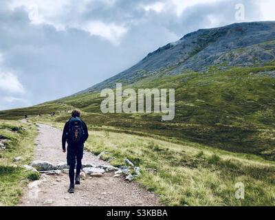 A man walks on a path near the Ben Nevis mountain range in Scotland in the UK Stock Photo