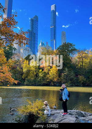 Mother and daughter enjoying the pond in central park on a sunny autumn afternoon, 2021, USA Stock Photo