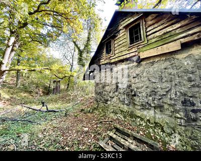 Traditional log and stone cottage abandoned. Forlorn house in the woods. Stock Photo