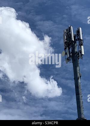 A cell tower set against an early springtime blue sky and billowing clouds. Stock Photo