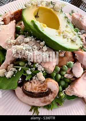 Close up of chicken and avocado salad on a bed of greens with fresh English peas and white mushrooms Stock Photo