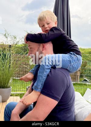 Little boy sitting on his father shoulders Stock Photo