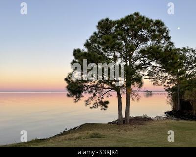Sunset over bay water with Novembers Beaver Moon in the distance Stock Photo