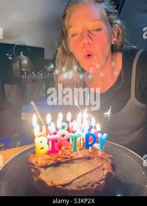 A woman blows out candles on a birthday cake in a tent in Wales Stock Photo