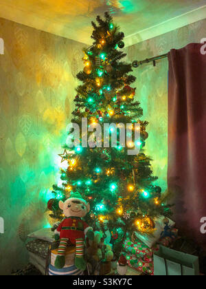 A Christmas tree lit up with green and yellow lights. Stock Photo
