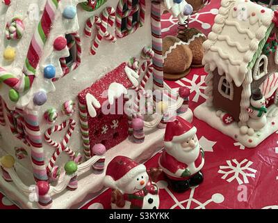 A ceramic gingerbread house and other Christmas decorations and knick knacks on a dining room table in a home in Utah, USA. Stock Photo