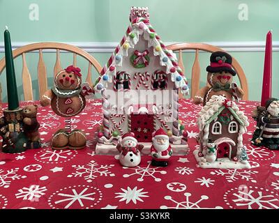 A ceramic gingerbread house and other Christmas decorations and knick knacks on a dining room table in a home in Utah, USA. Stock Photo
