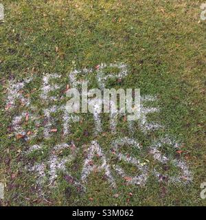Keep off the grass painted onto lawn Stock Photo