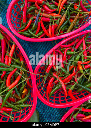 Baskets of red and green hot peppers on display at a farmer's market in ...