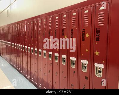 Looking down a high school hallway with red lockers. Apparently, these lockers belong to student choir members, each named for the member student. Stock Photo