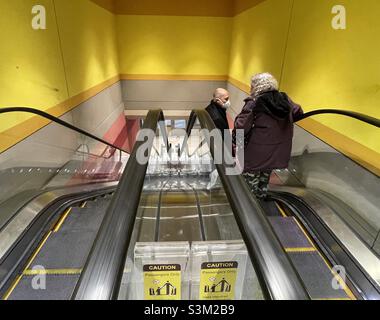 A couple of people going down on an escalator at the City Creek shopping complex in Salt Lake City, Utah, USA. Stock Photo