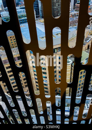 London city buildings seen from 23rd floor of apartment block,  through open window with safety grating. Spitalfields, London, England Stock Photo