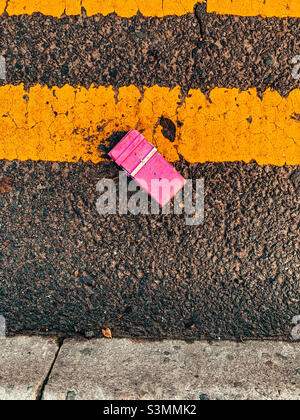 Pink belt laying on the road next to double yellow lines Stock Photo