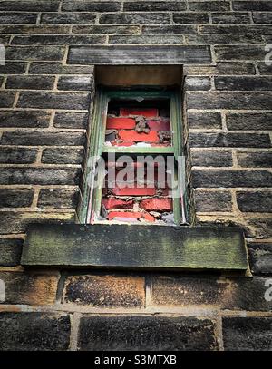 ‘A room without a view’ an old stone building has its windows blocked up with red bricks Stock Photo
