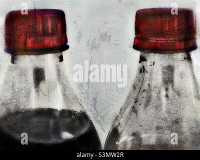 A stylized, with grunge effects, still life of two bottles of Vanilla Coke. One bottle is full while the other has the better part already consumed. Stock Photo