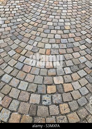 Closeup of granite paving stones laid in an arching or semi circular design. Stock Photo