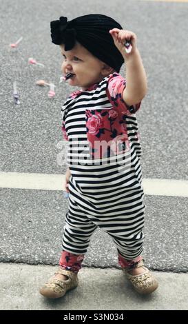 Baby girl collecting candy off the street at a parade Stock Photo