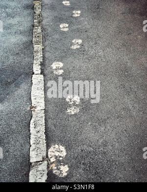 Painted footsteps on a pavement going off into the distance Stock Photo