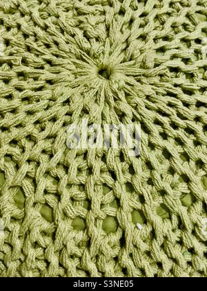 A knitted pouffe in thick green wool exhibiting a radial pattern Stock Photo