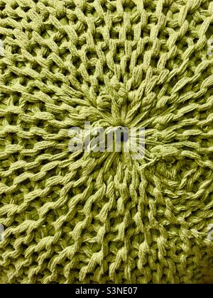 A close-up of a knitted pouffe, showing a radial pattern of stitches in a thick green wool Stock Photo