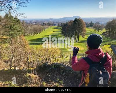 Walker at the rest and be thankful viewpoint on Corstorphine Hill, with a view over Murrayfield golf course towards Arthur’s Seat, Edinburgh Stock Photo