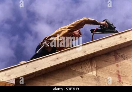 Construction worker Builder working on roof of house Stock Photo