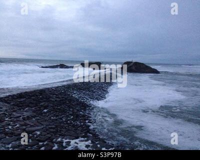 Waves starting to come over Bude breakwater Stock Photo