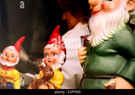 Garden gnomes on display with woman in background Stock Photo
