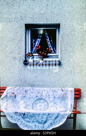 Lace tablecloth on red bench outside Berlin flat Stock Photo