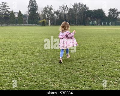 Small child running across playing field Stock Photo