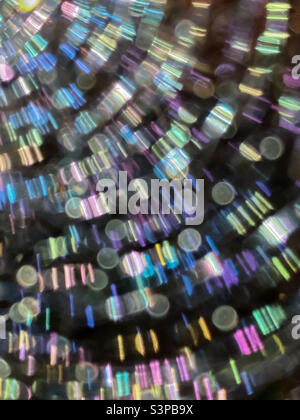 Abstract of bright, multi-colour lines of circles and bars cascading down diagonally against a black background (sunlight on a spider web inside a hollow tree stump). Stock Photo