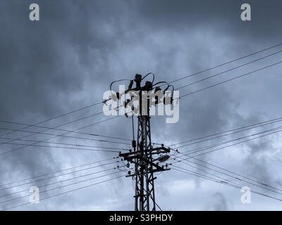 Silhouette of electricity pylon against dark ominous sky Stock Photo