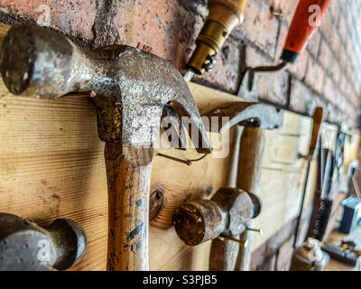 Tools including claw hammers hung on wall Stock Photo