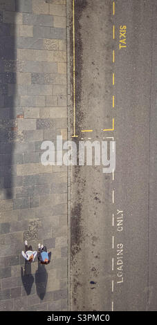 Two people on pavement casting shadows from above Stock Photo